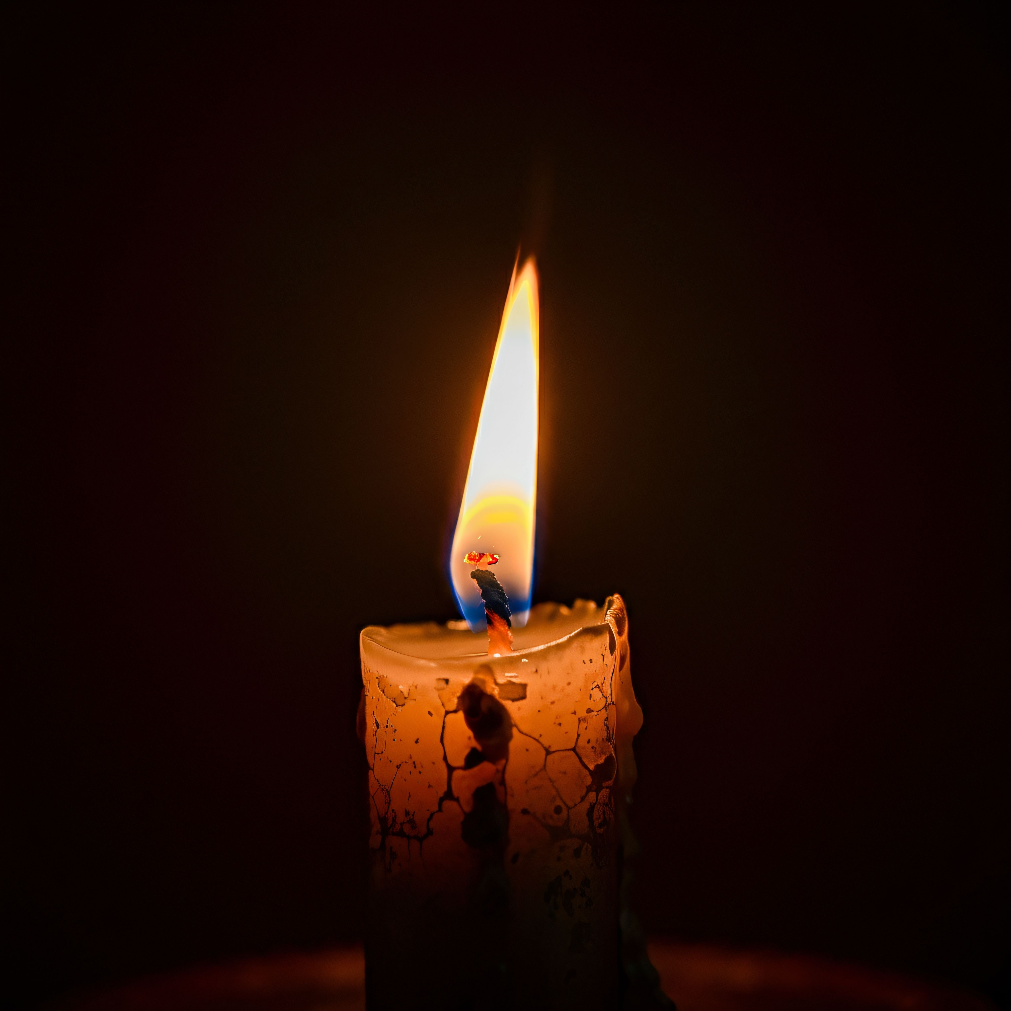 A lit pillar candle in the dark — Charles Waweru on Pexels