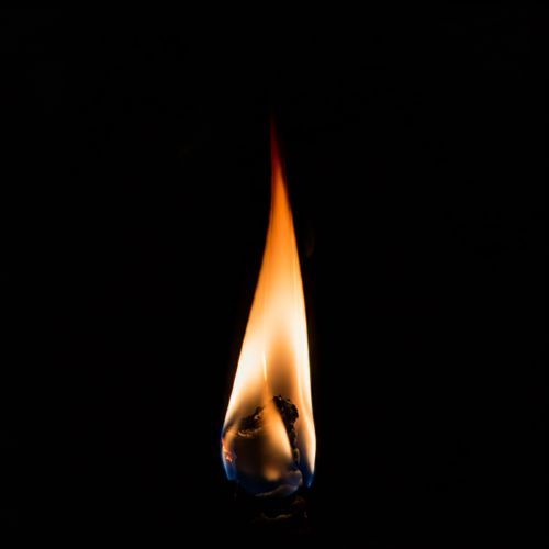Free A vivid candle flame against a black background, highlighting its warm glow. Stock Photo