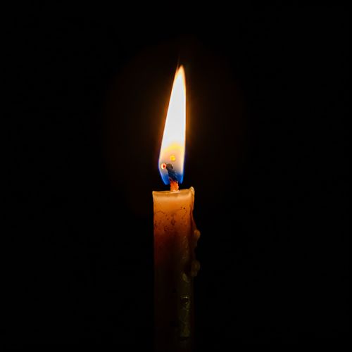 Free Close-up of a candle flame glowing in the dark, symbolizing hope and tranquility. Stock Photo