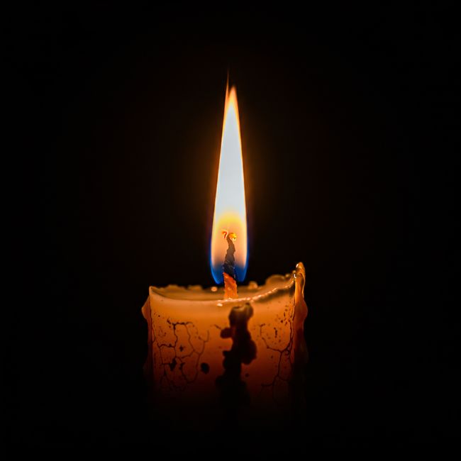 A solitary candle illuminates the darkness with a warm, soft glow.