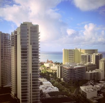 Photo by Alec Doualetas Downtown Honolulu skyline with high-rise buildings and ocean view under a blue sky.