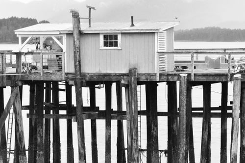 Free A wooden stilt house on a dock, set against a serene water backdrop in Hoonah, Alaska. Stock Photo