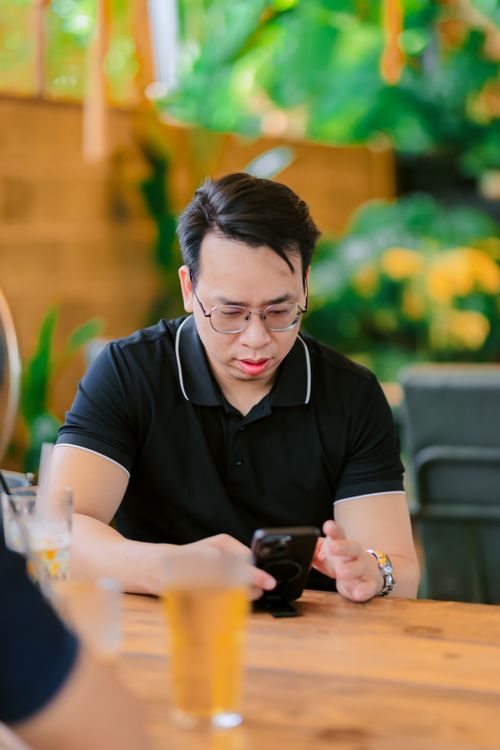 Free A man attentively looking at his smartphone while enjoying a drink in a cozy cafe environment. Stock Photo