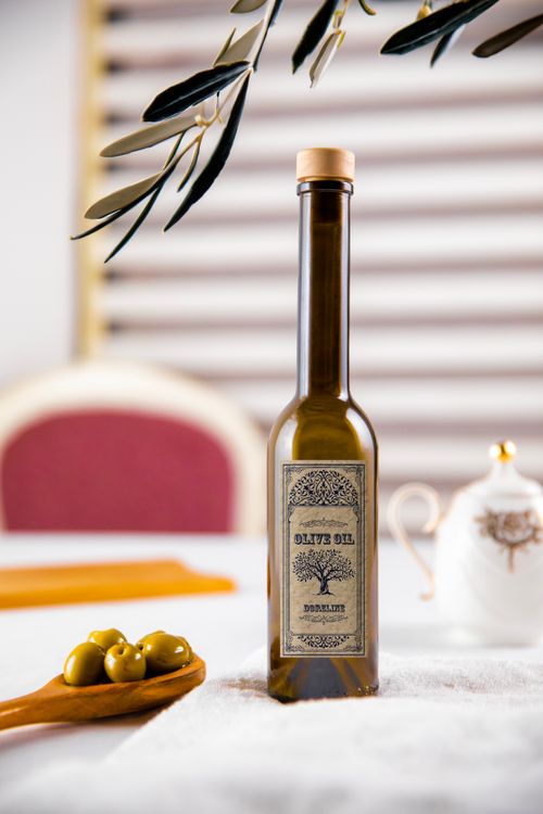 Free A rustic olive oil bottle presented with fresh olives and a teapot on a white tablecloth. Stock Photo