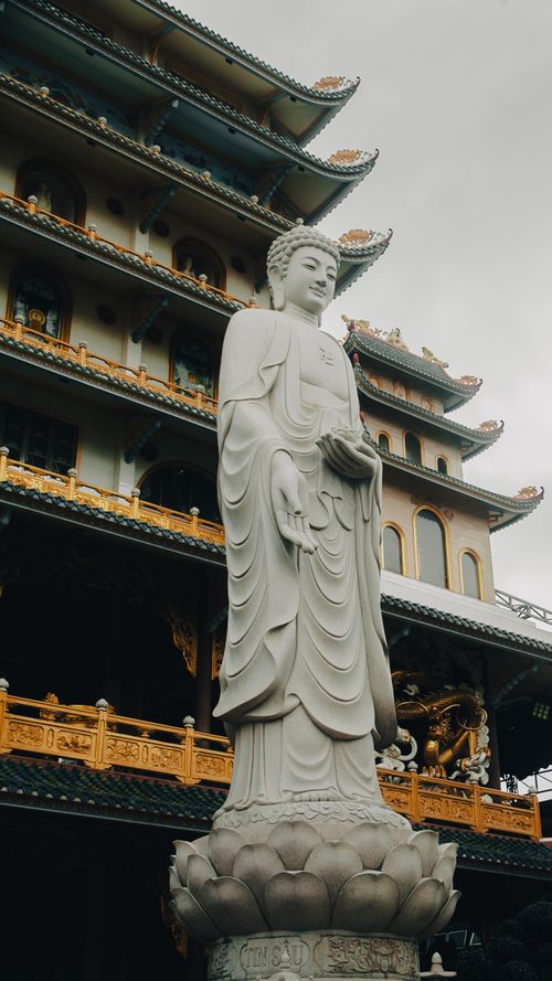 Free Majestic Buddha statue in Ho Chi Minh City, Vietnam against a multi-tiered pagoda. Stock Photo