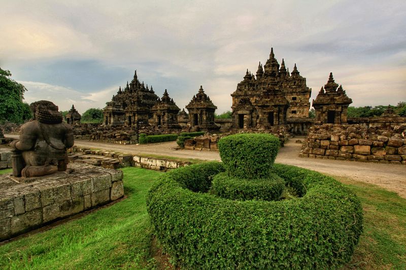 Plaosan temple shrines framed by stone statues and manicured hedges in Central Java