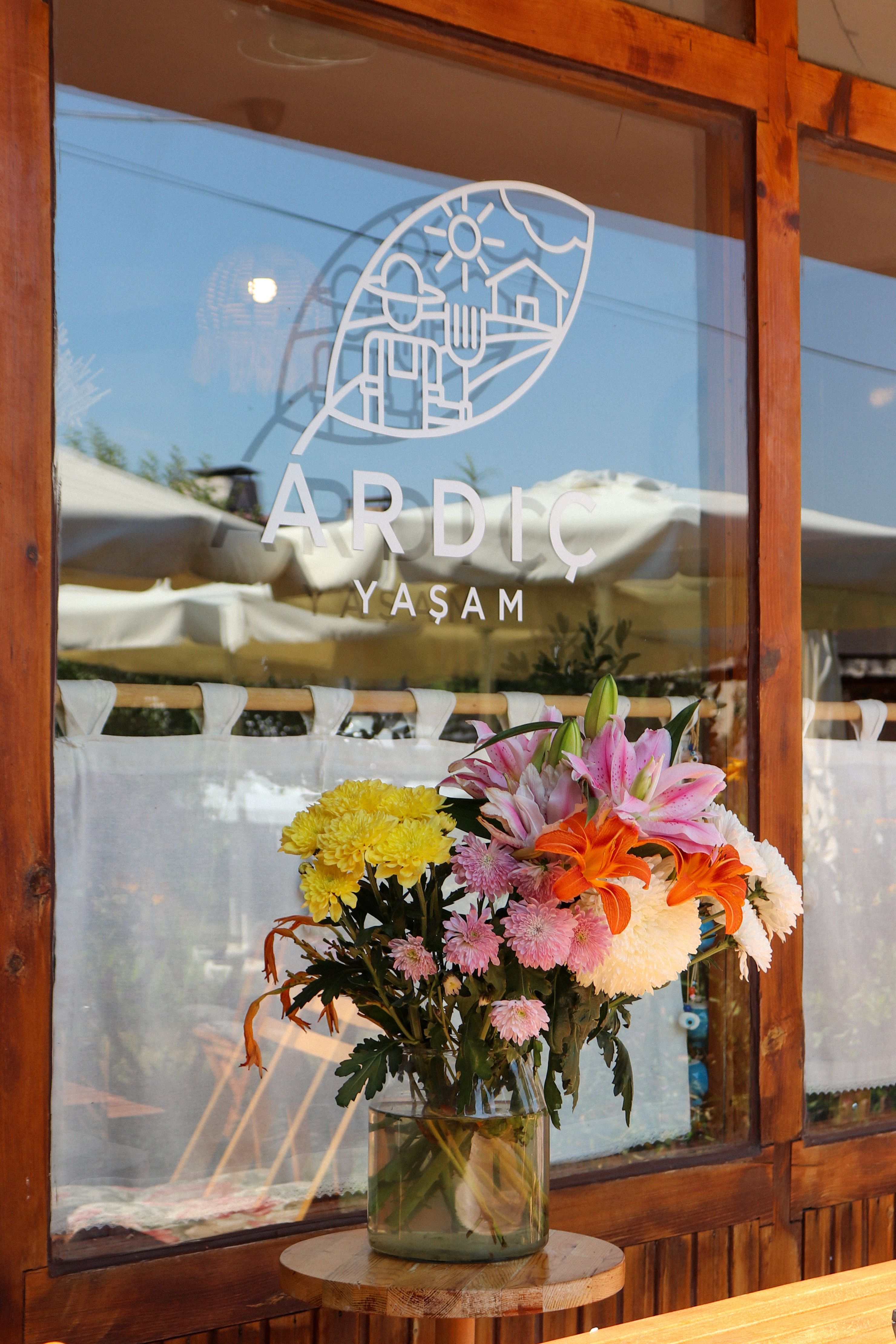 Colorful floral arrangement at a cafe with wooden decor and logo signage.