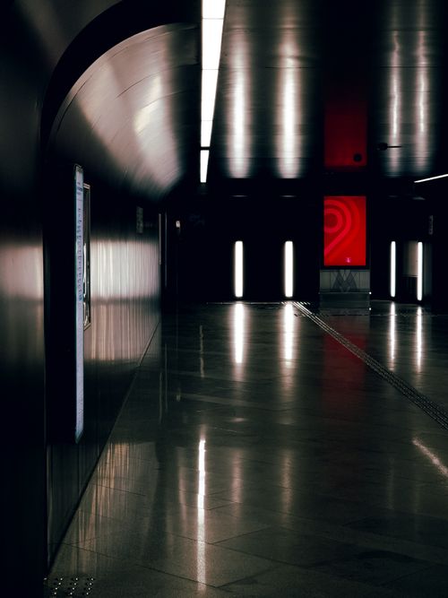 Free A modern, glossy underground passage with reflective surfaces and striking red light. Stock Photo