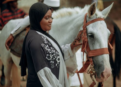 Free An African woman gently caresses an Arabian horse, embracing cultural heritage and connection with animals. Stock Photo
