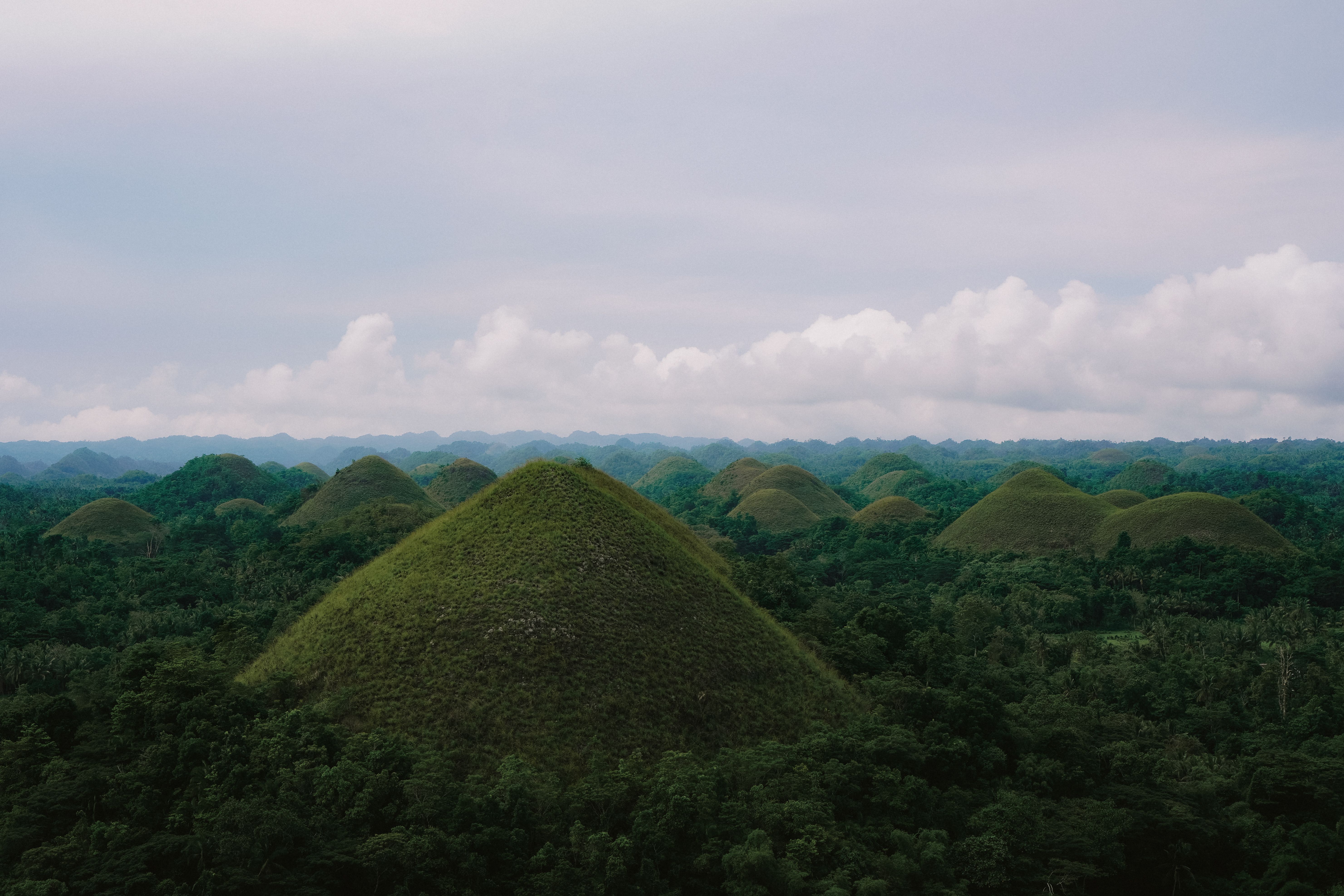 Breathtaking aerial perspective of the iconic Chocolate Hills in Bohol, Philippines under a vast sky.