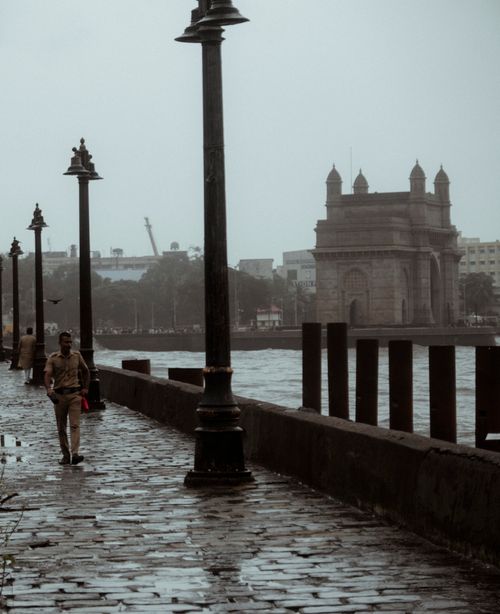 Free A rainy day by the Gateway of India in Mumbai featuring a lone walker on wet cobblestones. Stock Photo