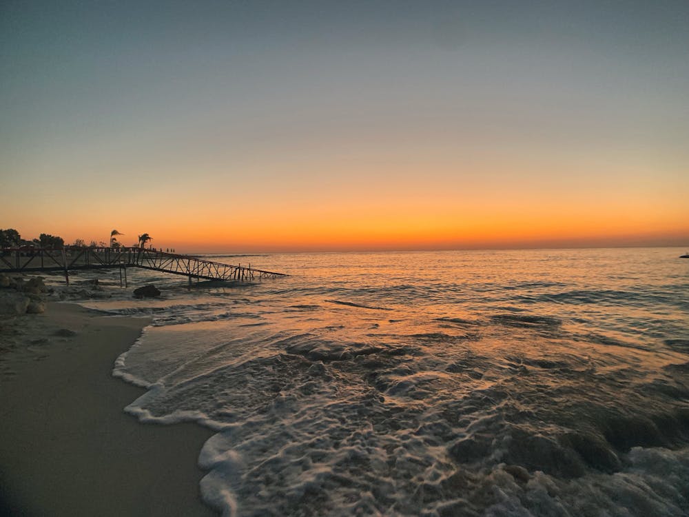 Free Sea Waves Crashing on Shore during Sunset Stock Photo