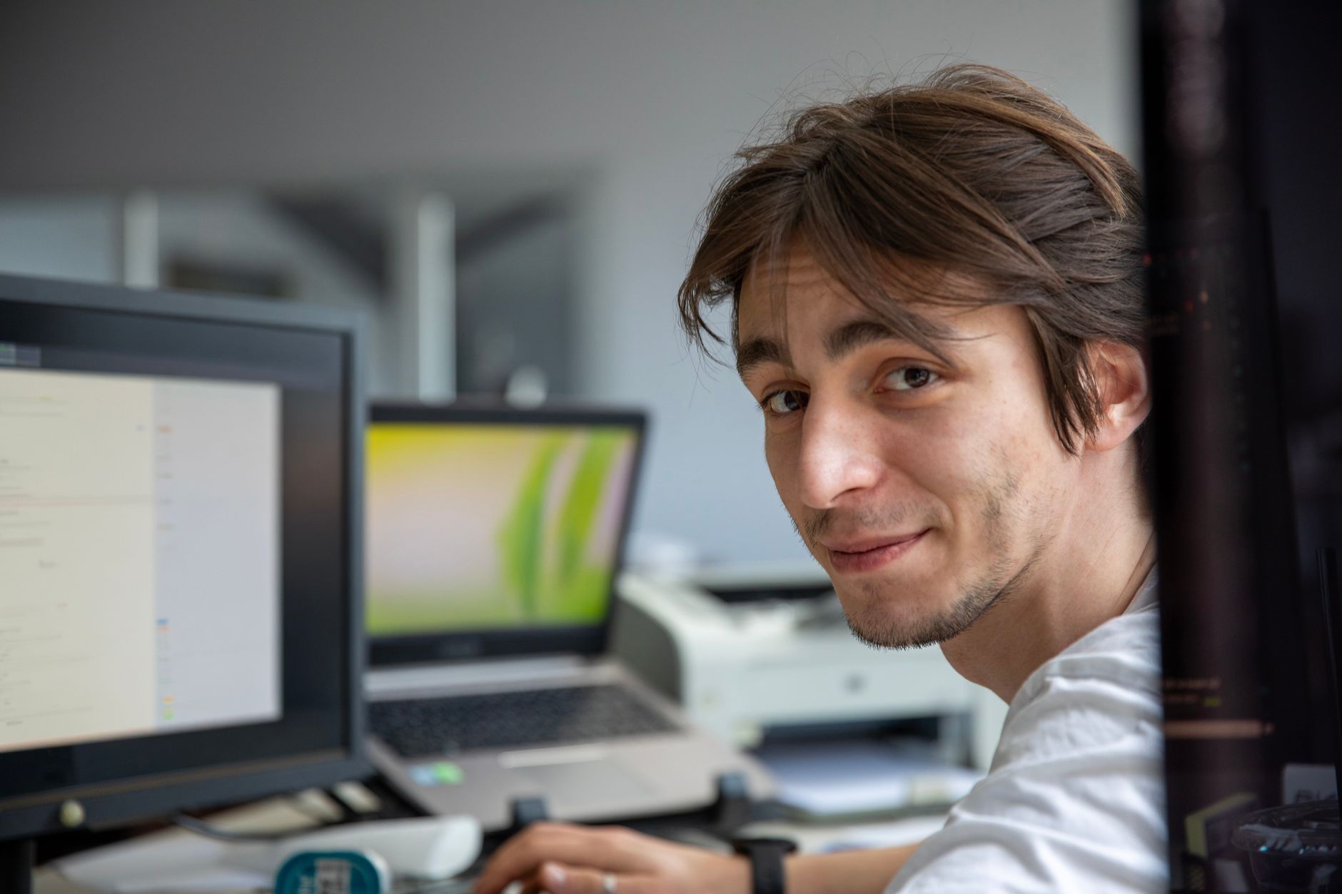 A young professional working at his desk in a contemporary office environment.