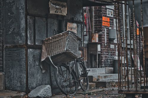 Free Old bicycle with a wicker basket against an industrial backdrop. Nostalgic and vintage feel. Stock Photo