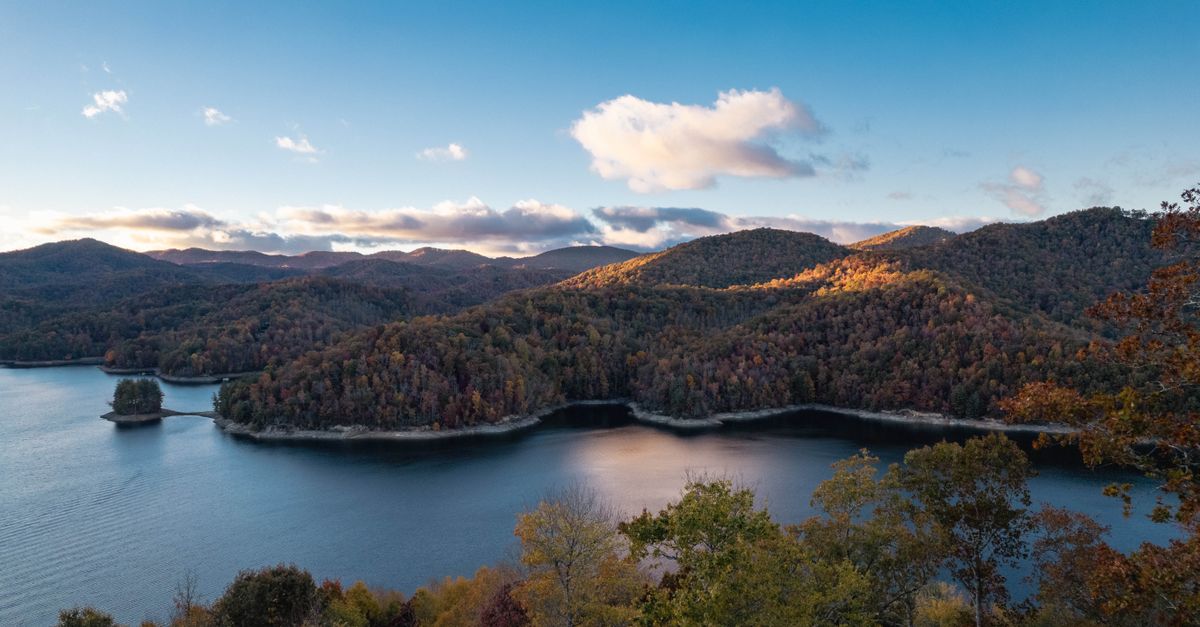 A stunning view of a mountain lake surrounded by vibrant autumn forest at dusk.
