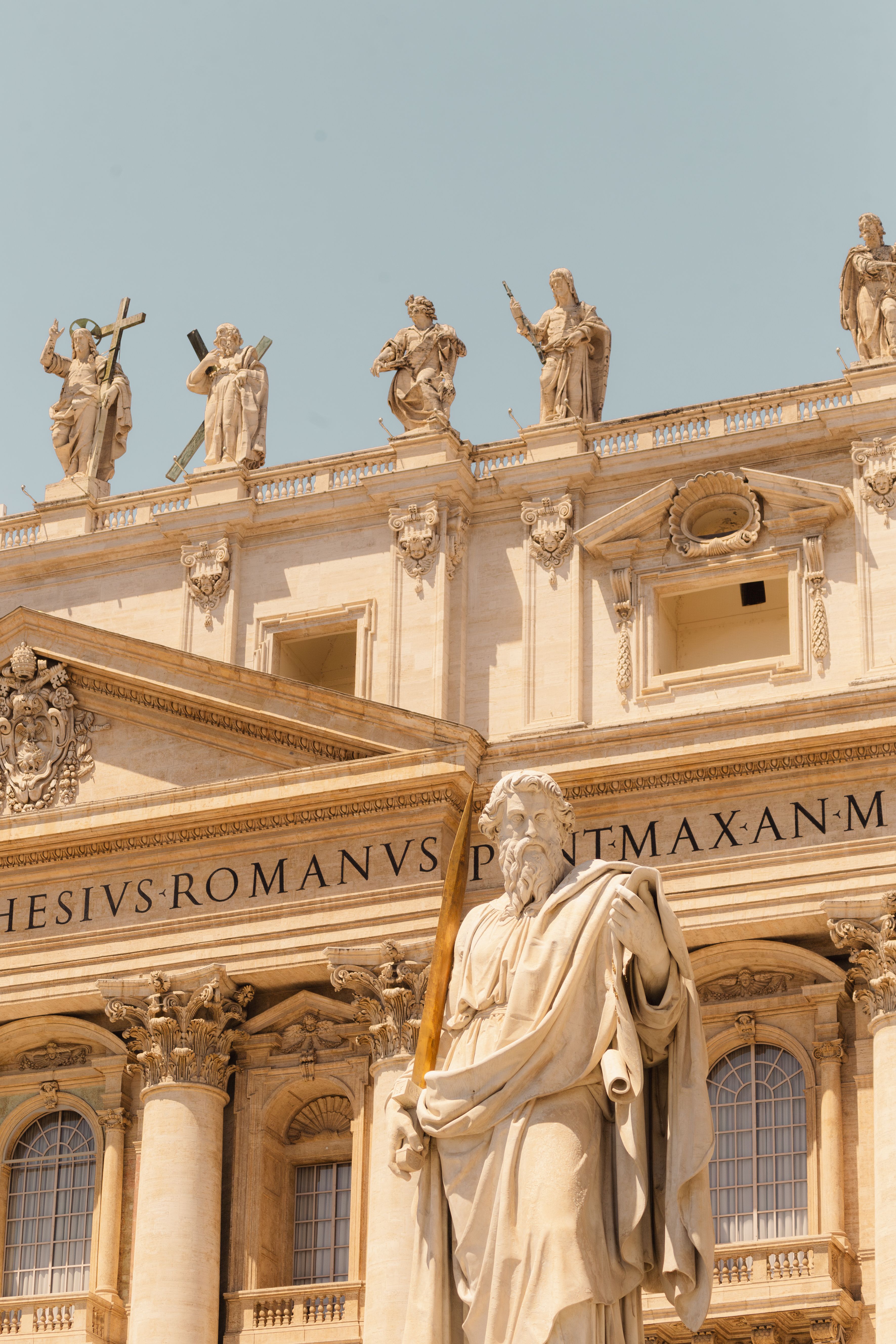 Facade of St. Peter's Basilica featuring statues against a clear sky in Rome, Italy.