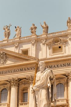 Facade of St. Peter's Basilica featuring statues against a clear sky in Rome, Italy.