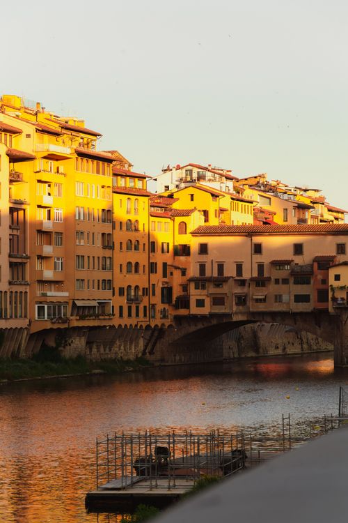 Free Golden hour light on Ponte Vecchio in Florence, reflecting in the Arno River. Stock Photo