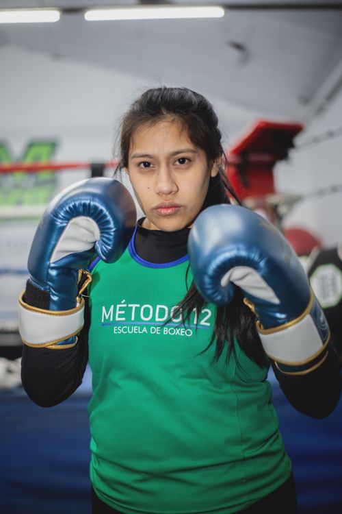 Free Focused female boxer in training at a Buenos Aires boxing gym, wearing blue gloves. Stock Photo