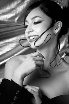 Black and white artistic portrait of a smiling woman with stylish hair twirls, creating an elegant and classic look.
