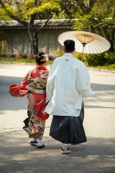 A couple in traditional Japanese attire strolling outdoors in Osaka, Japan.