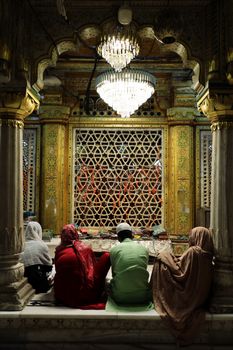 Worshippers seated in front of intricate latticework at Hazrat Nizamuddin Dargah, New Delhi.