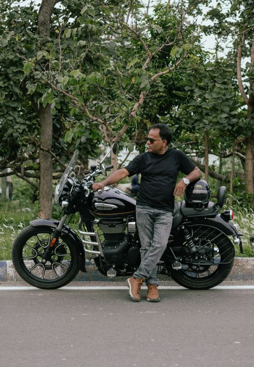 Free Man in black tee leaning on a motorcycle on a city street, Kolkata. Stock Photo