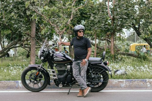 Free A man poses with a motorcycle in a green outdoor setting in Kolkata, India. Stock Photo