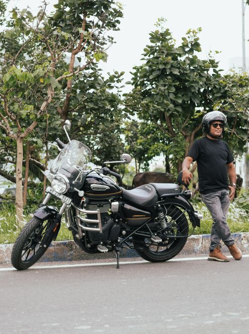 Free South Asian man poses by motorcycle on an urban street in Kolkata, surrounded by greenery. Stock Photo
