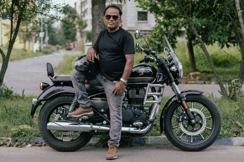 Free Man standing beside his Royal Enfield motorcycle in Kolkata, India, exuding confidence. Stock Photo