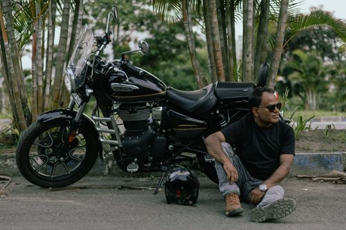 Free A man sits casually beside a Royal Enfield motorcycle in Kolkata, India. Stock Photo