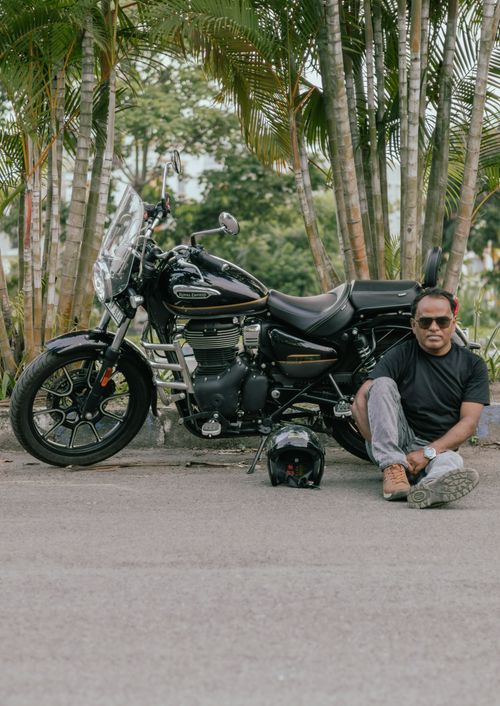 Free Casual portrait of a man sitting beside a motorcycle in a tropical setting, Kolkata, India. Stock Photo