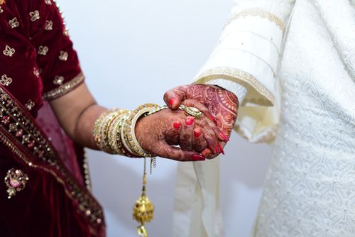 Free Close-up of bride and groom's hands during traditional South Asian wedding, featuring intricate mehndi and jewelry. Stock Photo