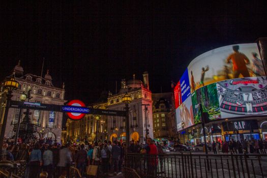 Bustling crowd at iconic Piccadilly Circus under vibrant LED advertisements at night.
