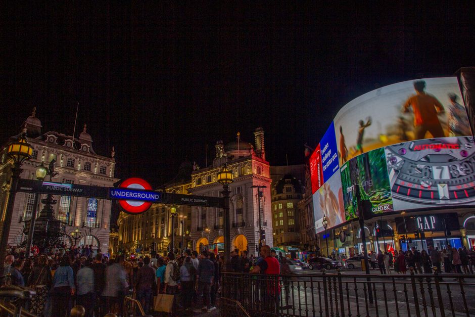 Bustling crowd at iconic Piccadilly Circus under vibrant LED advertisements at night.