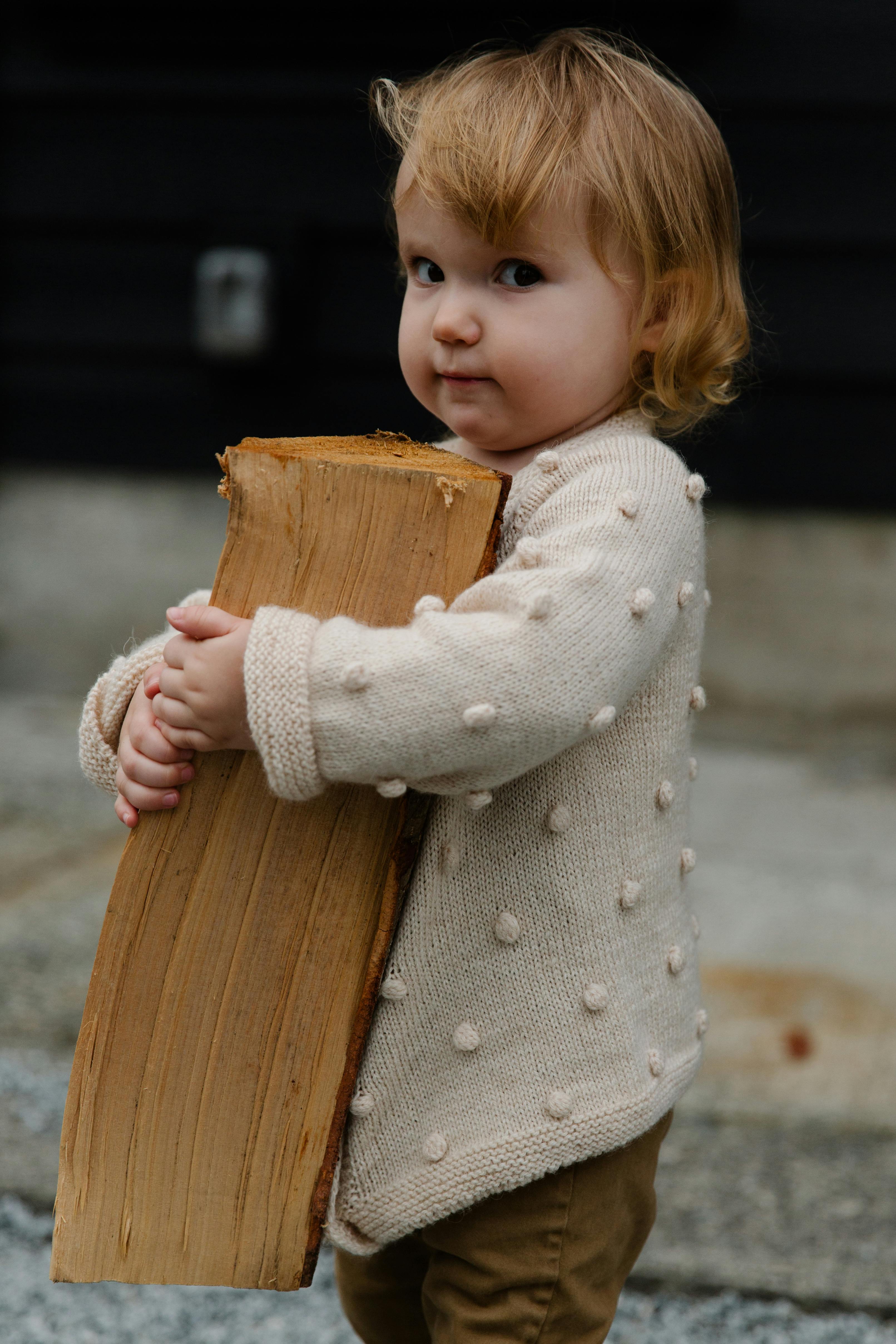 girl in white sweater holding brown wooden log