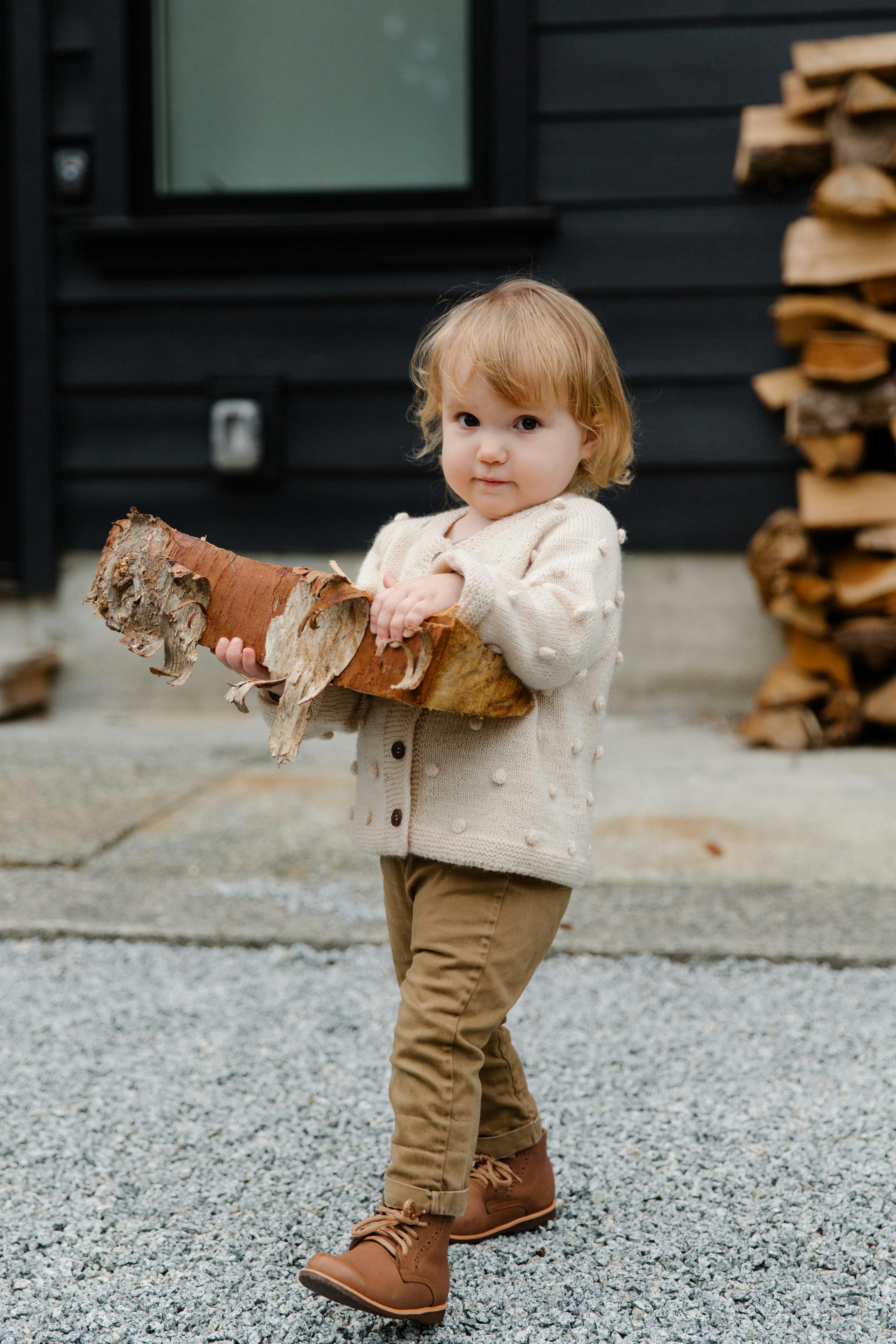 funny kid with firewood walking in yard