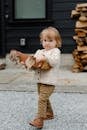 Funny kid with firewood walking in yard