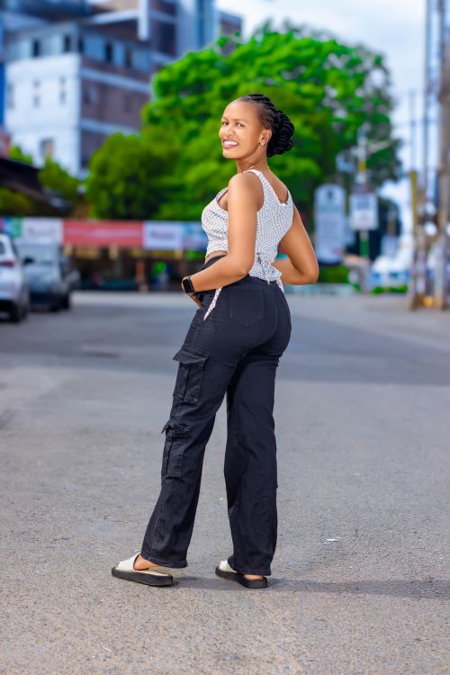Free A smiling young woman poses confidently on a city street, showcasing fashion style. Stock Photo