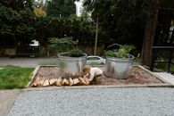 From above side view of little child wearing casual clothes putting firewood on ground near metal flowerbed and working on backyard