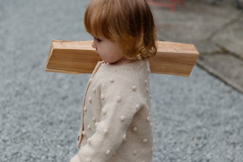 Little girl holding firewood and going to build