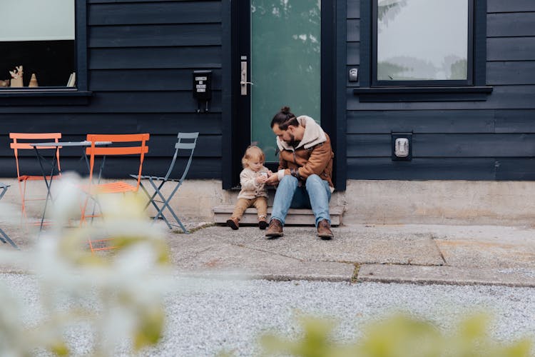 Father And Child Sitting Near Door In Backyard