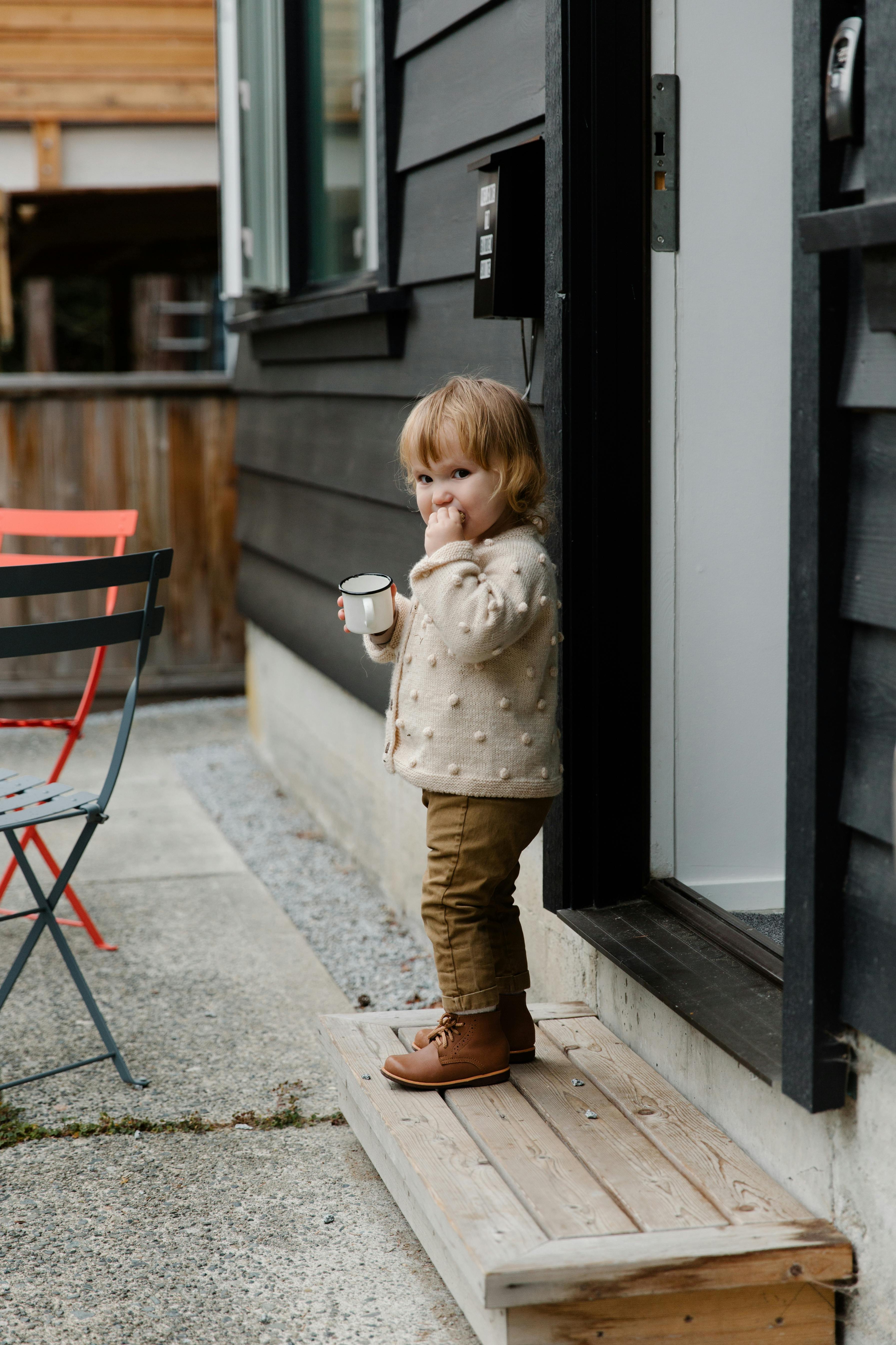 little girl with cup of drink standing on stairs