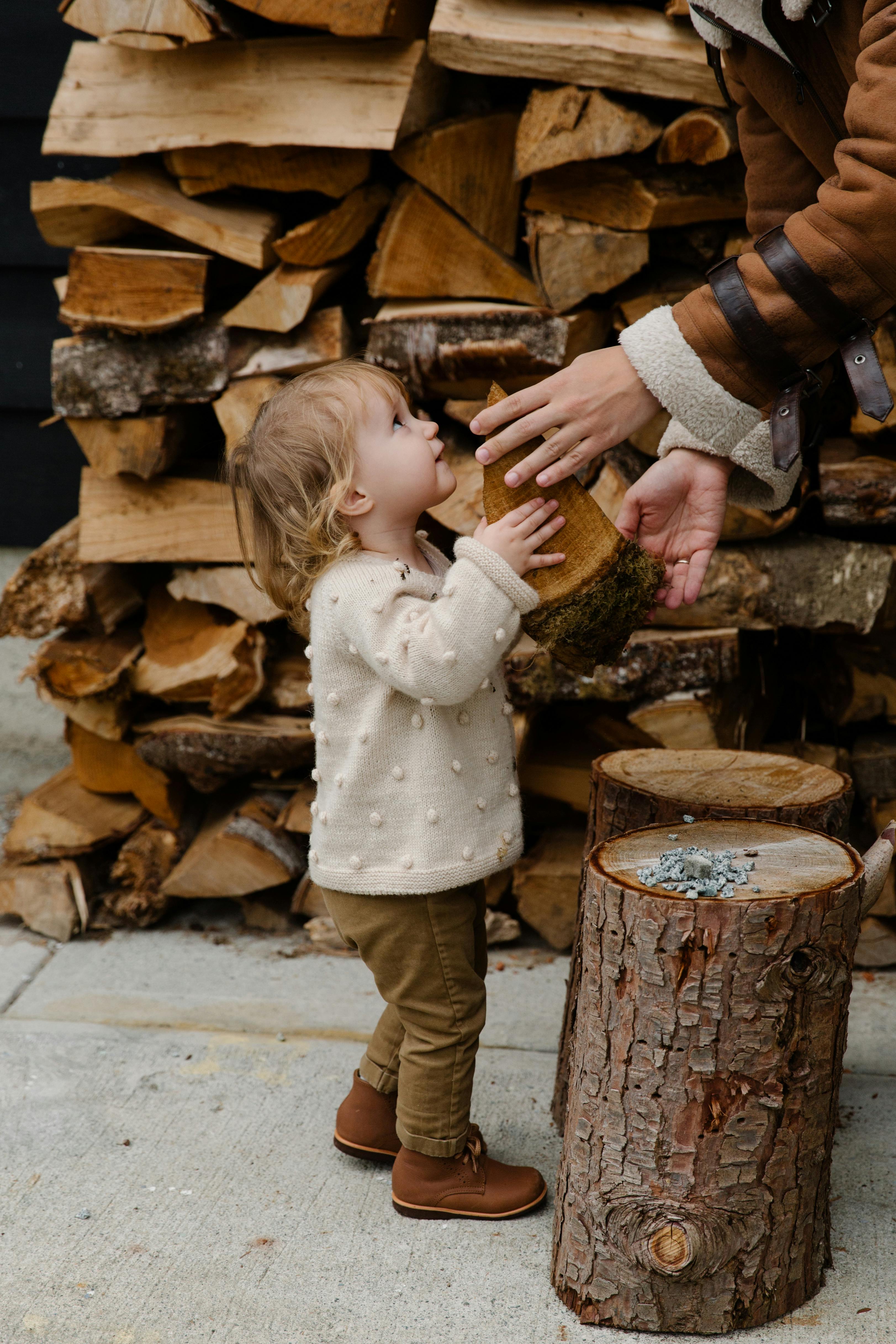 little girl looking at father standing near firewood