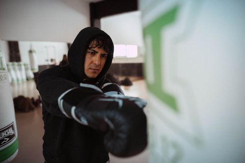 Free Focused boxer training indoors, punching a bag with intensity. Stock Photo