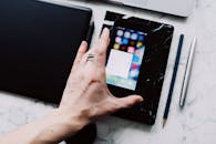 Anonymous crop person using smartphone while working with gadgets on table