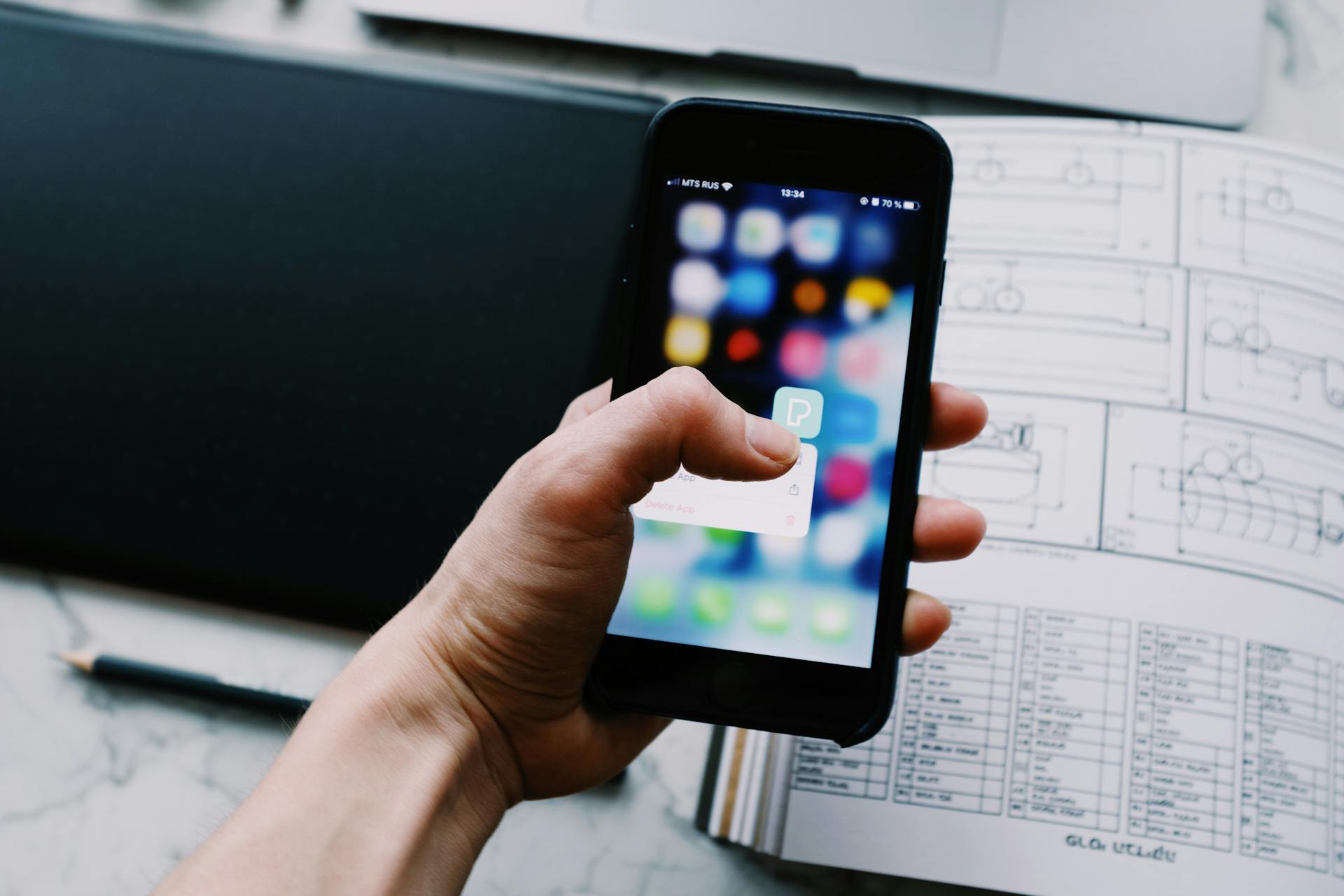 A hand holding a smartphone, showcasing a blurred app interface in an office setting.