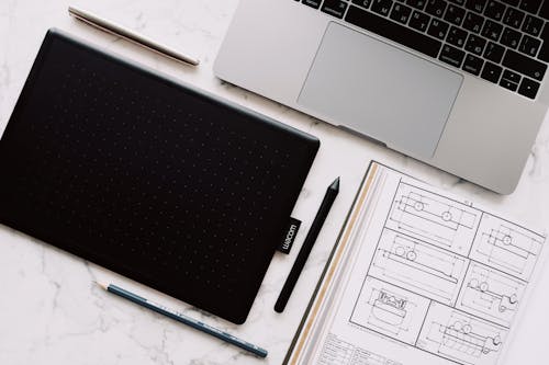 Black and Silver Macbook Pro Beside Black Pen