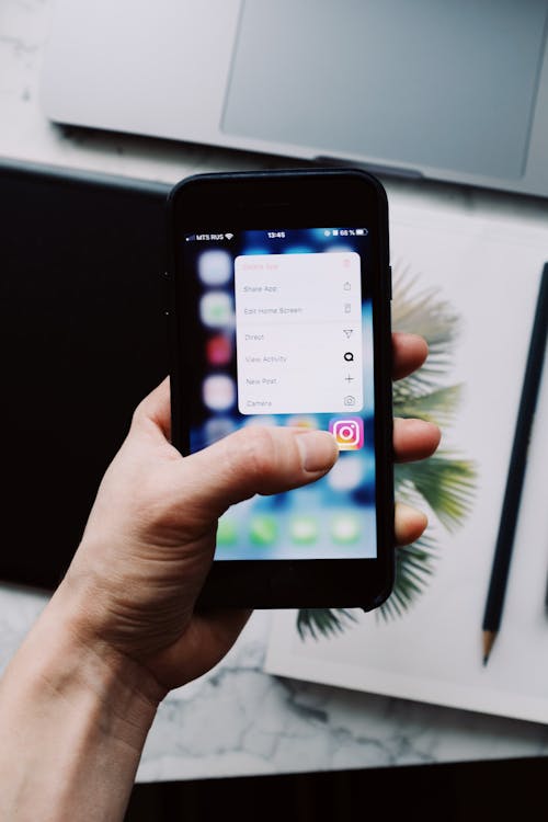 Instagram 앱 삭제 및 재설치하기 - 누군가의 손에 삭제 옵션이 표시된 Instagram 아이콘이 있는 휴대폰이 들려 있습니다.