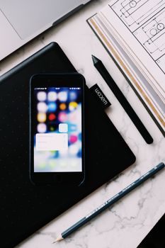Top view of cellphone with pop up window on blurred screen and book with drawing located on marble table near marker and pencil